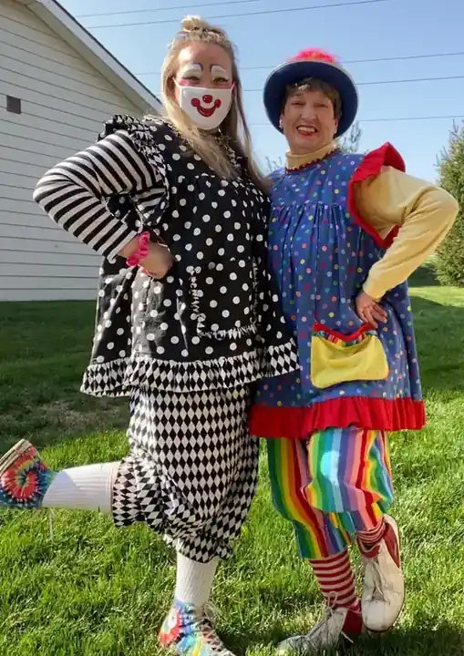 Two Clowning Around clowns in costume, polka dots and stripes, on a lawn