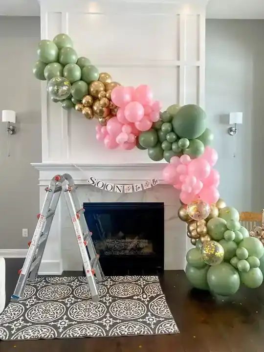 Pastel pink and sage organic balloon garland climbing a white fireplace mantel