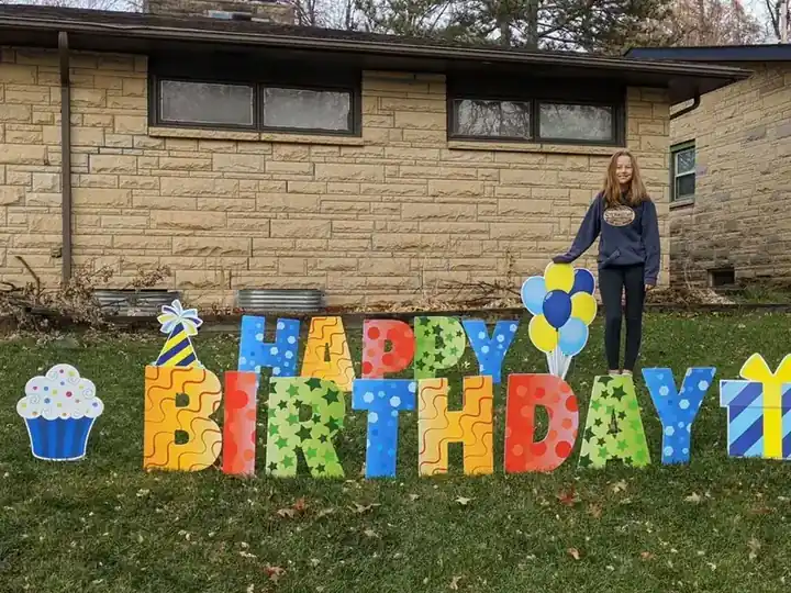 Colourful HAPPY BIRTHDAY yard letters with balloons on a front lawn