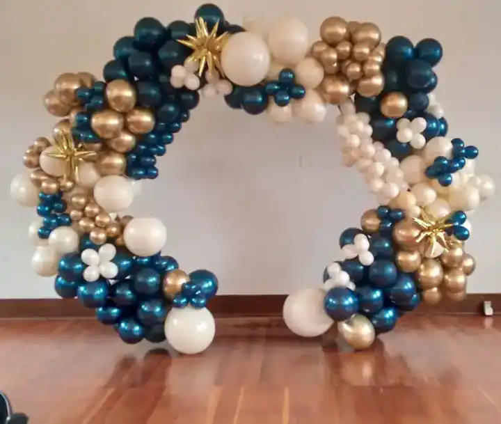Navy, gold and white organic balloon arch standing on a wood floor