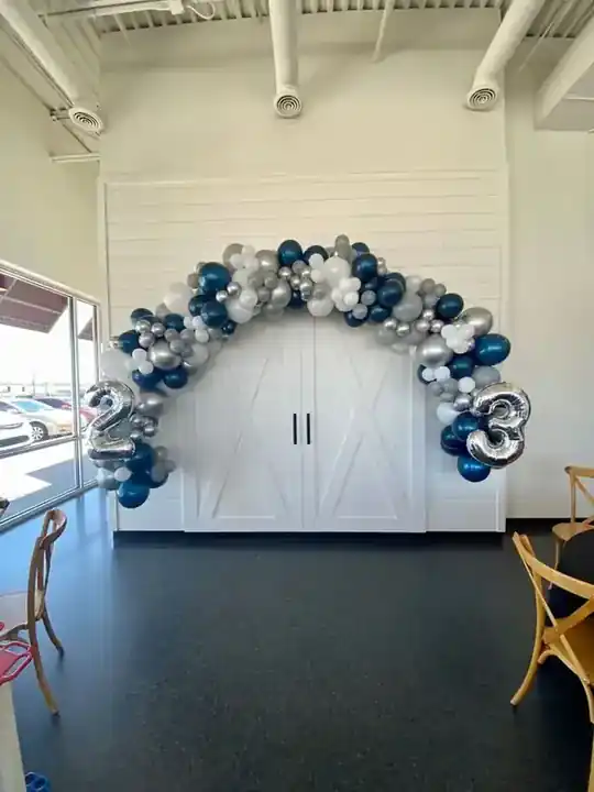 Navy, silver and white balloon arch over a white barn door
