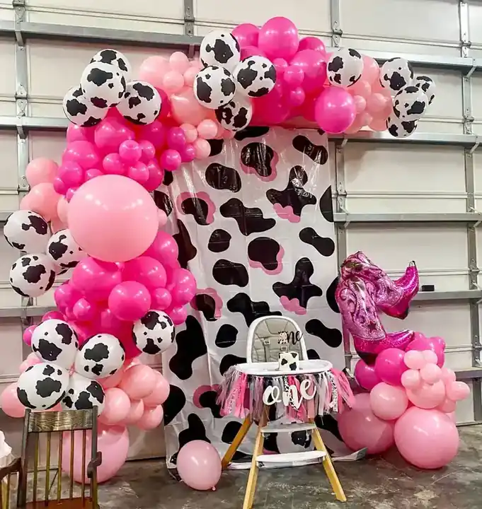 Hot pink and cow-print balloon garland around a first-birthday high chair