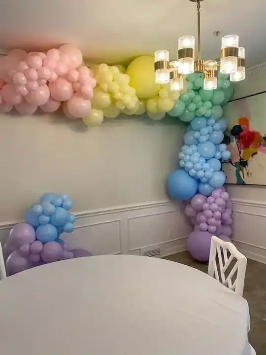 Pastel rainbow balloon garland in the corner of a dining room