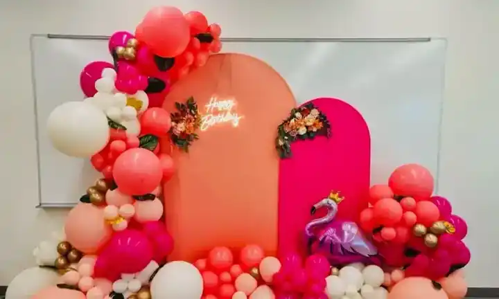 Coral, pink and white balloon garland over arched party backdrops