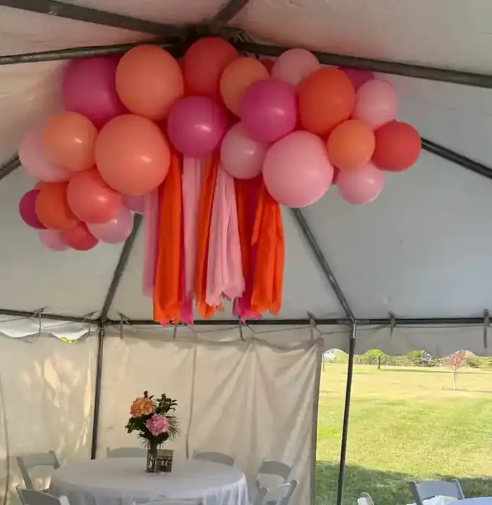 Coral and pink balloon cloud hanging over a tent dessert table