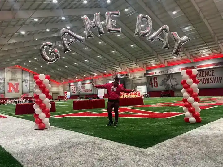 GAME DAY foil letters and red spiral columns across an indoor practice field