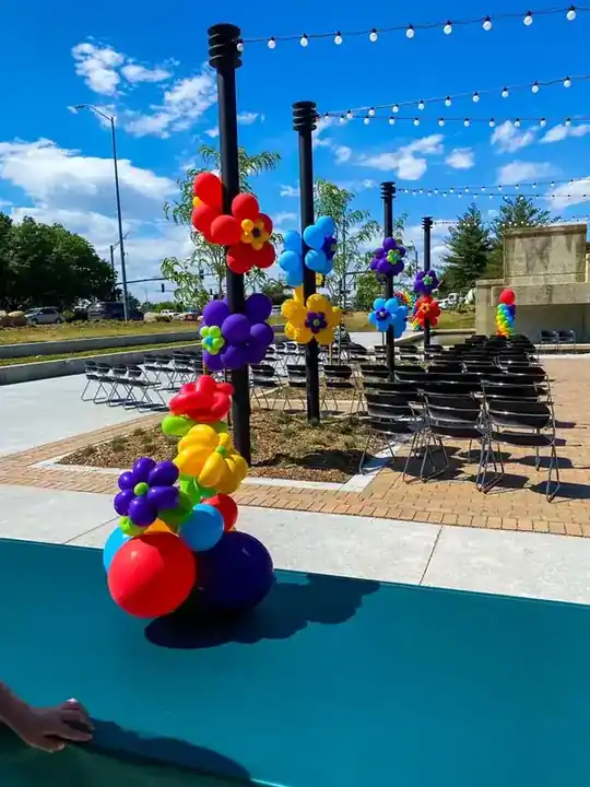 Rainbow balloon column beside a pool under string lights