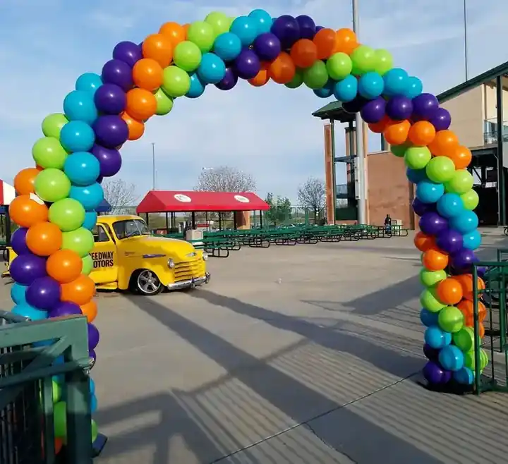 Rainbow balloon arch outdoors at a ballpark plaza