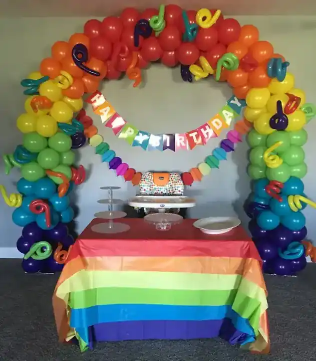 Rainbow balloon arch over a dessert table with a birthday banner